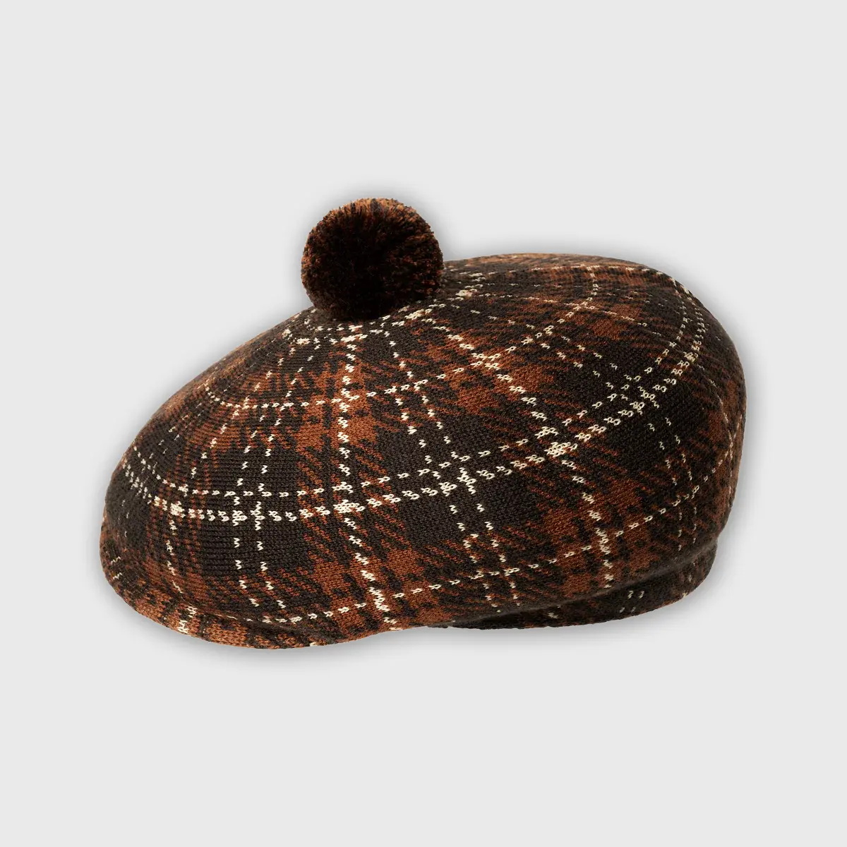 Kangol Golfer pet in bruin en roestoranje ruitpatroon, zijaanzicht dat de gebreide textuur en de pompon bovenop toont.