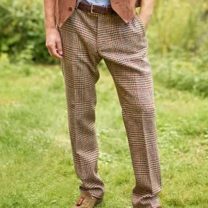 Pantalon en tweed Harris à carreaux écossais sable, porté par un homme debout dans un jardin.