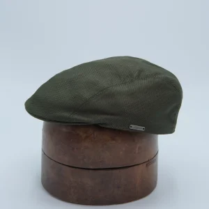 Casquette plate étroite en coton vert olive. Posée sur une forme à chapeau.