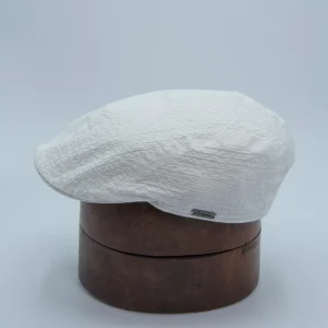 Casquette plate étroite en coton seersucker blanc. Posée sur une forme à chapeau.