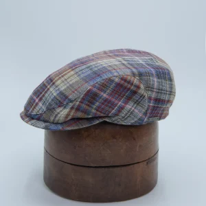 Linnen flat cap in multikleur waaronder rode accenten, grijs, groen, blauw, ruiten op, flat cap zit op een malle.