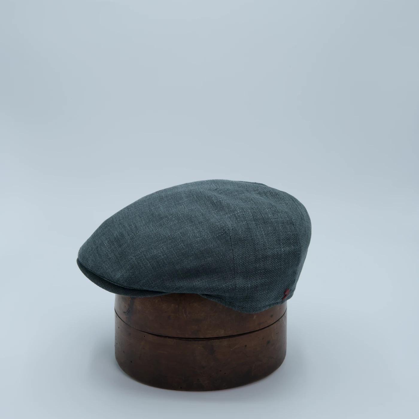 Casquette plate vert cendré, en tissu Zegna premium, présentée sur une tête de présentation